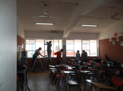 Instalación de ventanería de aluminio con cristal claro en aulas de la escuela durante proceso de obra.