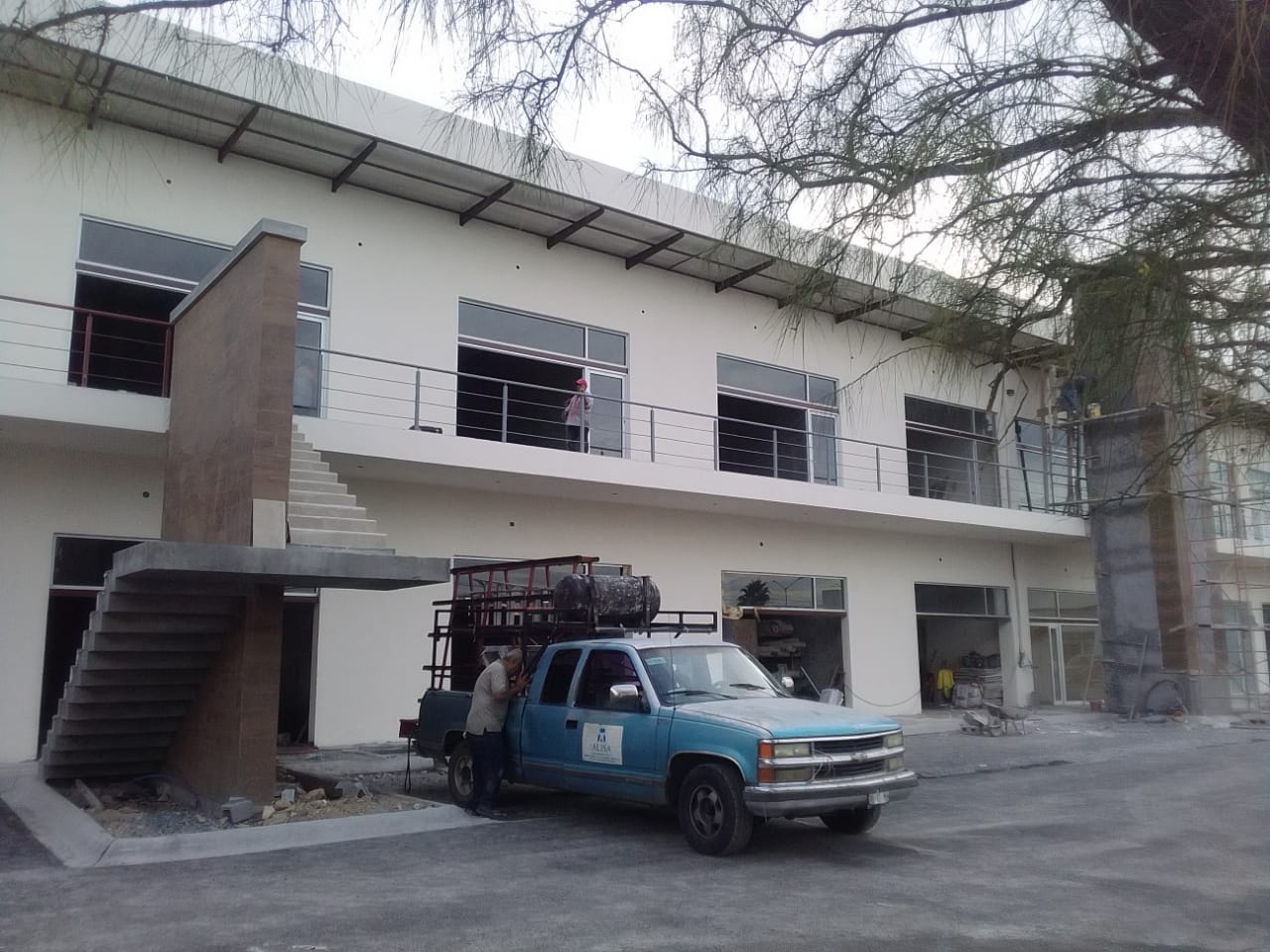 Locales comerciales en planta baja y alta con ventanería de aluminio y cristal, balcón con barandal metálico color rojo.