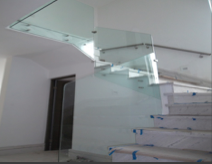 Barandal de cristal templado curvo en escalera interior, sin perfil superior visible para vista despejada.