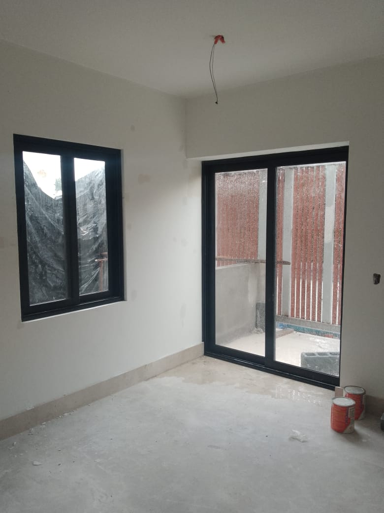 Ventana fija y puerta corrediza de dos hojas en aluminio negro con cristal claro, abriendo recámara a balcón privado.