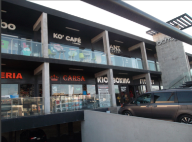 Barandal de cristal templado en pasillo de locales comerciales, integrando vista despejada hacia la fachada.