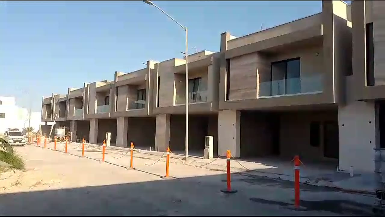 Cancelería corrediza panorámica integrada a fachada contemporánea con acabados en travertino y madera.