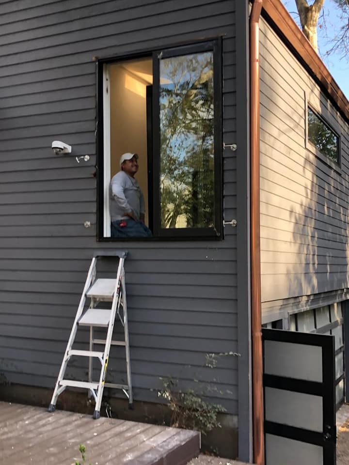 Instalación de ventana abatible de gran formato en aluminio negro durante el proceso de montaje en obra.